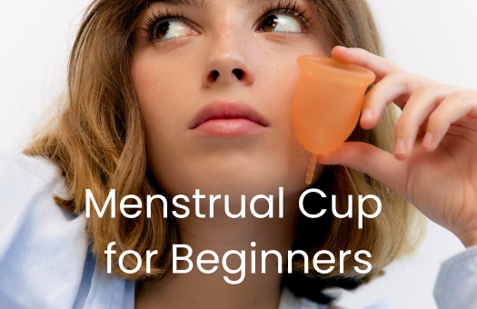 Young woman holding an orange menstrual cup beside her face with the text Menstrual Cup for Beginners