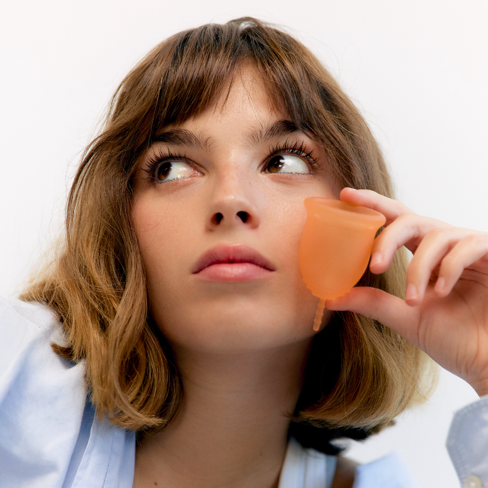 Woman holding a Lena silicone cup to her ear, listening intently.