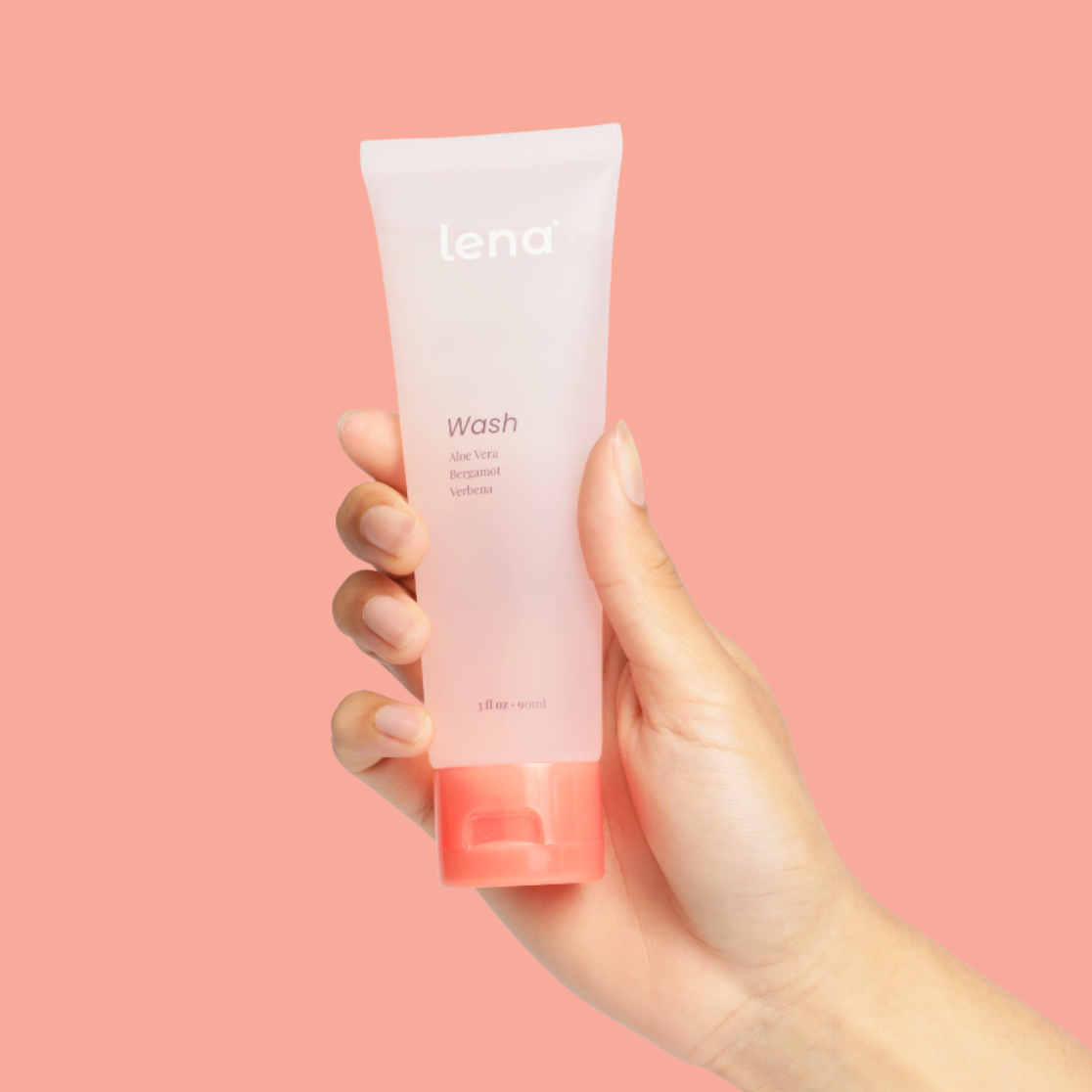 Hand holding a tube of 'lena' wash against a pink background