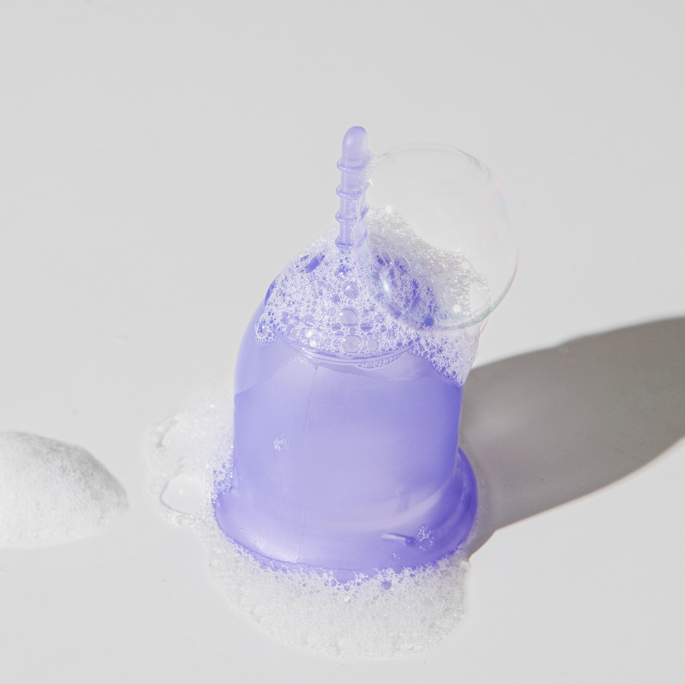 Purple silicone cup with a straw in a sink filled with water