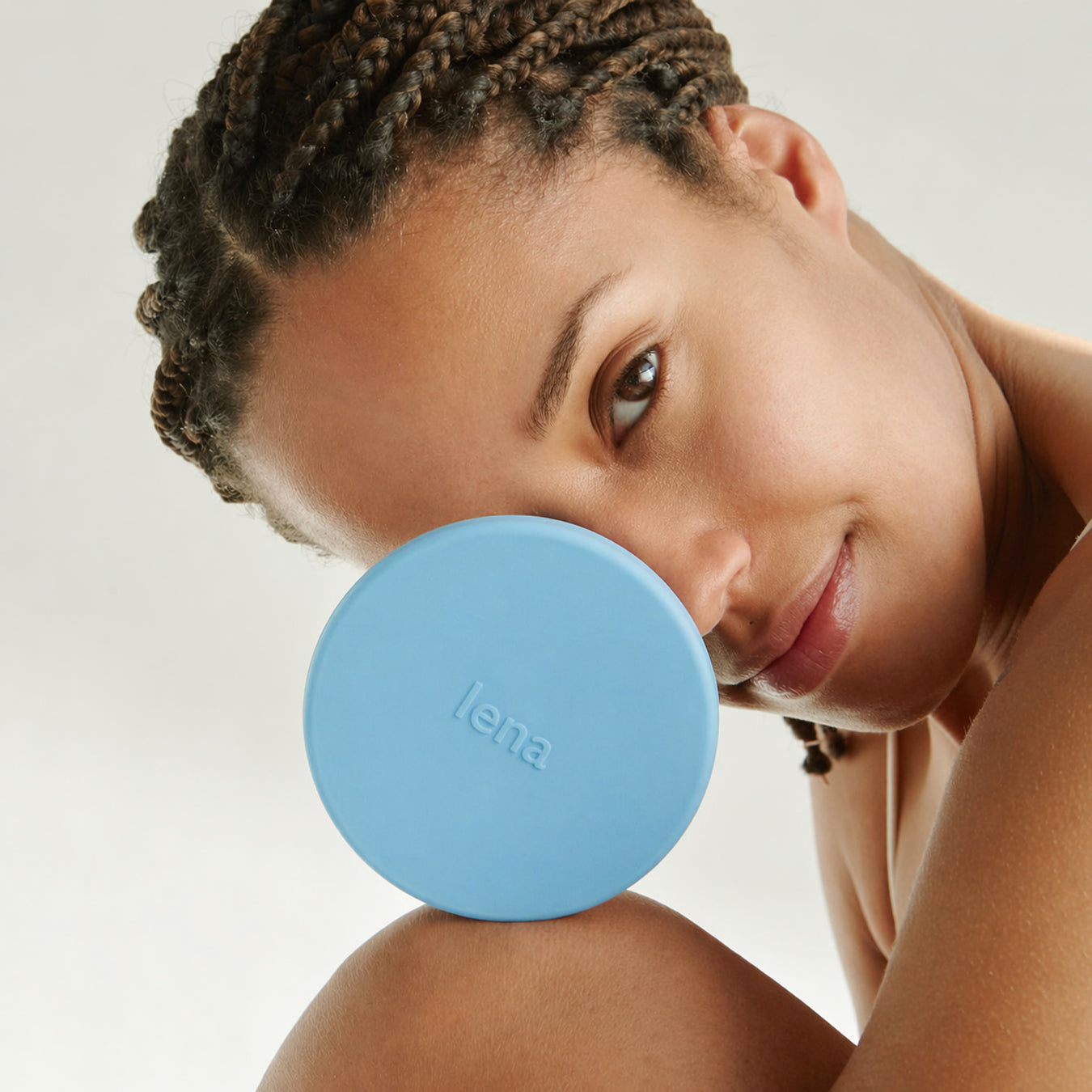Woman holding a blue round object with 'lena' branding against a neutral background