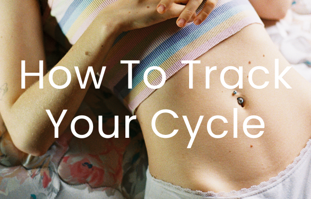 An image of a woman's abdomen, she has a belly button piercing. She is in a crop top and she has her hands over her chest. The text "How To Track Your Cycle" is overlaid on top.