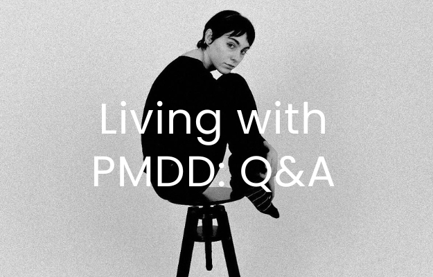 Woman on a stool looking at the camera, black and white image, with text overlaid 'Living with PMDD: Q&A'