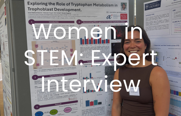 A woman stands smiling at the camera, stood in front of a presentation board of graphs and text. The text "women in STEM: Expert Interview" is overlaid