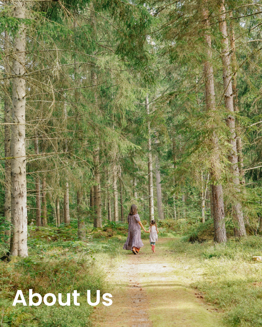 Two people walking down a path in a forest with 'About Us' text overlay.