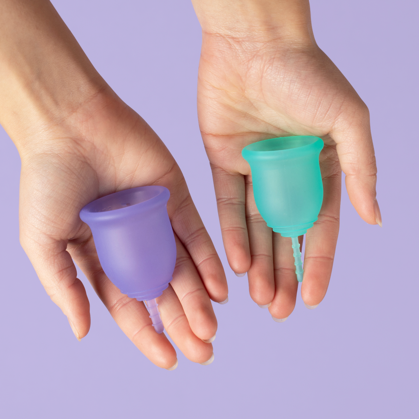 Two hands holding two menstrual cups - one in turquoise and one in purple
