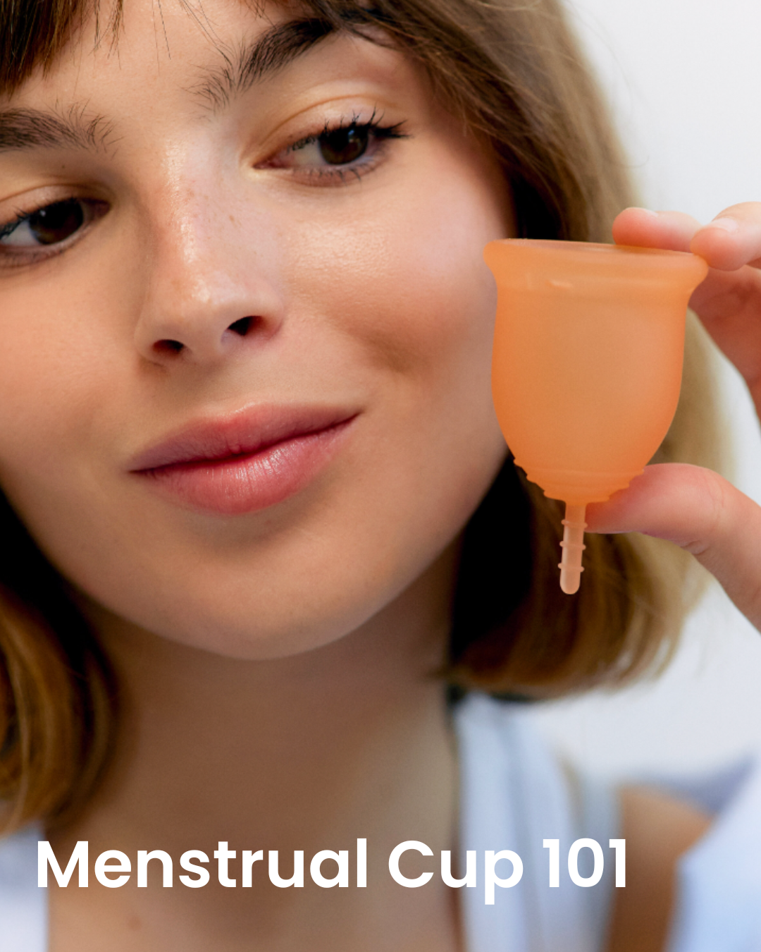 Person holding a coral menstrual cup with text 'Menstrual Cup 101' below.
